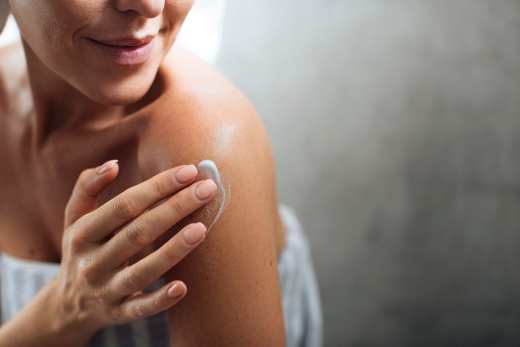 mujer aplicando crema en el cuerpo