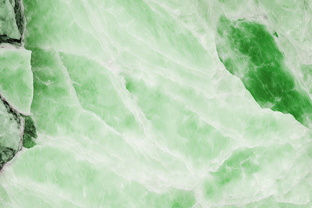 Primer plano de la textura de una piedra amazonita natural mostrando sus características vetas blancas y tonalidades verde jade.